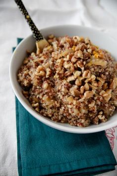 a white bowl filled with granola on top of a blue napkin next to a fork