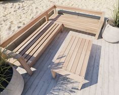 a wooden bench sitting next to a potted plant on top of a sandy beach