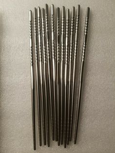 six stainless steel straws are lined up on a white counter top, one is black and the other is silver