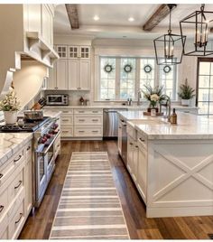 a large kitchen with white cabinets and wood flooring, along with an area rug