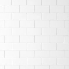 a white brick wall with a black and white cat sitting on top of it