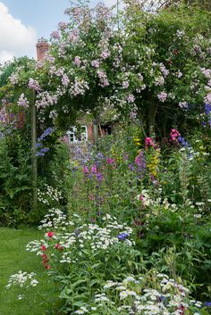 the garden is full of colorful flowers and greenery, along with an arch in the middle