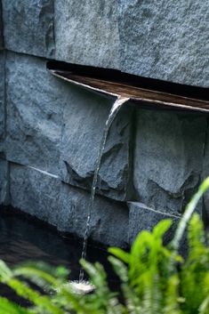 a water feature in front of a stone wall