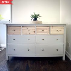 a white dresser with wooden drawers and a potted plant sitting on top of it