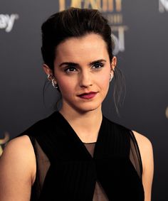 a woman in a black dress with red lipstick on the red carpet at an event