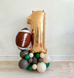 a balloon shaped number one sitting on top of a football and some other balloons in the shape of numbers