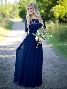 a woman in a long blue dress standing on a road