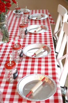 red and white checkered table cloth with plates, silverware and candlesticks