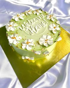 a green cake with white flowers and the words happy birthday on it sitting on a gold plate