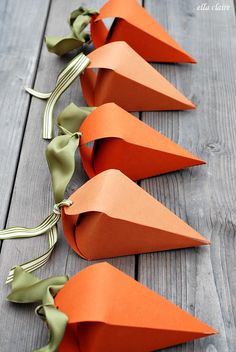 orange paper cones are lined up on a wooden table with green ribbons and bows attached to them