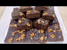 there are many pieces of brownies on the white plate with walnuts and nuts