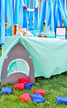 a shark tent is set up in the grass with blue streamers and decorations around it