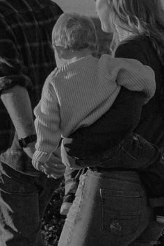 a man and woman holding a small child in their arms while standing next to each other