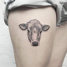 a small cow tattoo on the thigh