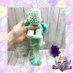 a hand holding a small crocheted stuffed animal in front of a wooden background