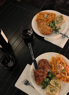 two white plates with food and wine on top of a wooden table next to each other