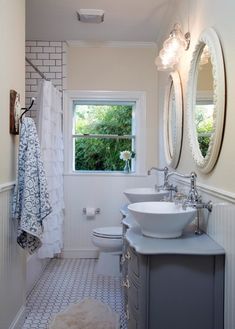 a white bathroom with two sinks and a mirror on the wall next to a toilet