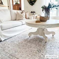 a living room with white couches and a coffee table in the middle of it