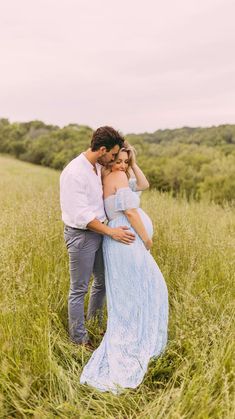 a pregnant couple cuddles in the tall grass