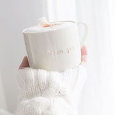 a person holding up a mug with the words leave you on it in gold lettering