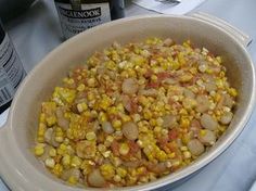 a large bowl filled with corn next to a bottle of wine and a can of beer