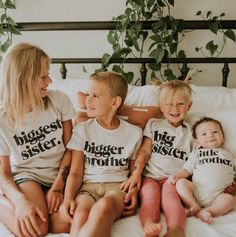 three children sitting on a bed with their mom and dad wearing matching t - shirts