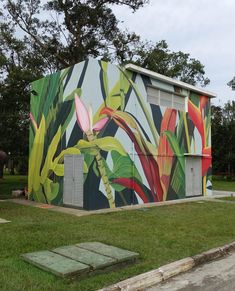 a colorful building painted with flowers and leaves on it's side in the grass