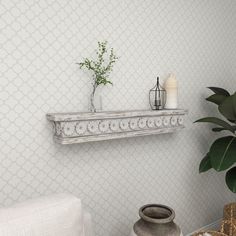 a white shelf sitting on top of a wall next to a potted plant