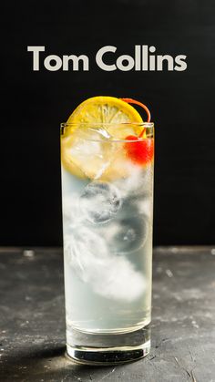 a tall glass filled with ice and lemon wedges on top of a table next to a sign that says tom collins