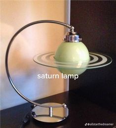 a green lamp sitting on top of a black table next to a white and gray wall