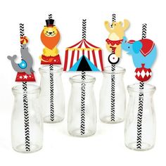 some glass vases filled with paper animals and striped straw flags in front of a tent