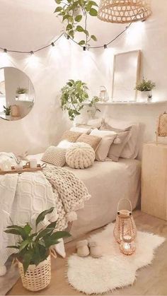 a bedroom with white walls and wooden flooring, potted plants on the bed