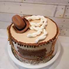 a cake with white frosting and brown icing on it, topped with a cowboy hat