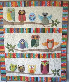 an owl themed quilt hanging on a wall