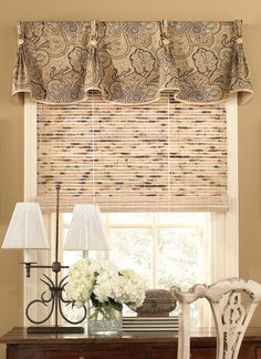 a room with a desk, chair and window covered in roman blind shades on the windowsill