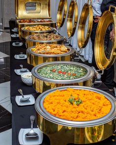 a buffet table filled with lots of different types of food and silver platters on top of it