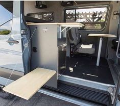 the interior of a van with its door open and wood flooring in front of it