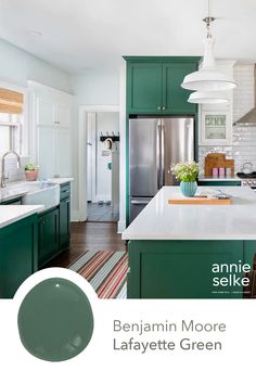 a kitchen with green cabinets and white counter tops, an island in front of the refrigerator