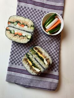 two sushi rolls with carrots, celery and cucumber on a checkered towel