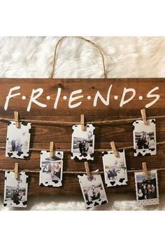 a wooden sign that says friends hanging on clothes pegs with pictures pinned to it