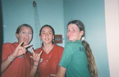 three young women standing next to each other making the peace sign in front of them