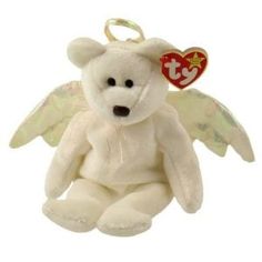 a white teddy bear with angel wings and a tag on it's ear is sitting in front of a white background