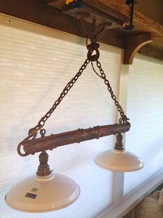 two lights are hanging from a beam in the ceiling with chains attached to each pole