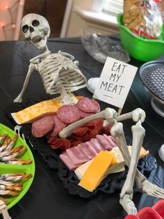 a table topped with lots of different types of meats and cheeses next to a sign that says eat my meat