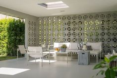 an outdoor living area with white furniture and greenery on the walls, along with a pergolated wall