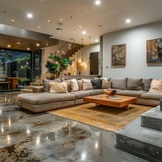 a living room filled with lots of furniture next to a stair case in front of a large window