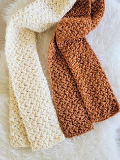 two crocheted scarves laying next to each other on a white furnishing