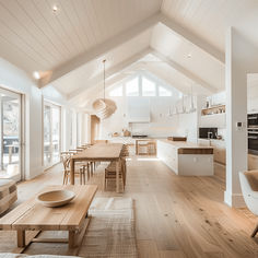 a large open concept kitchen and dining room with wood flooring, white walls and vaulted ceiling