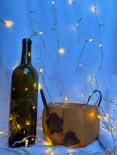 a wooden bowl and wine bottle with fairy lights in the background on a white cloth