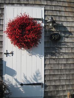 a door with a wreath hanging on it's side next to a light pole